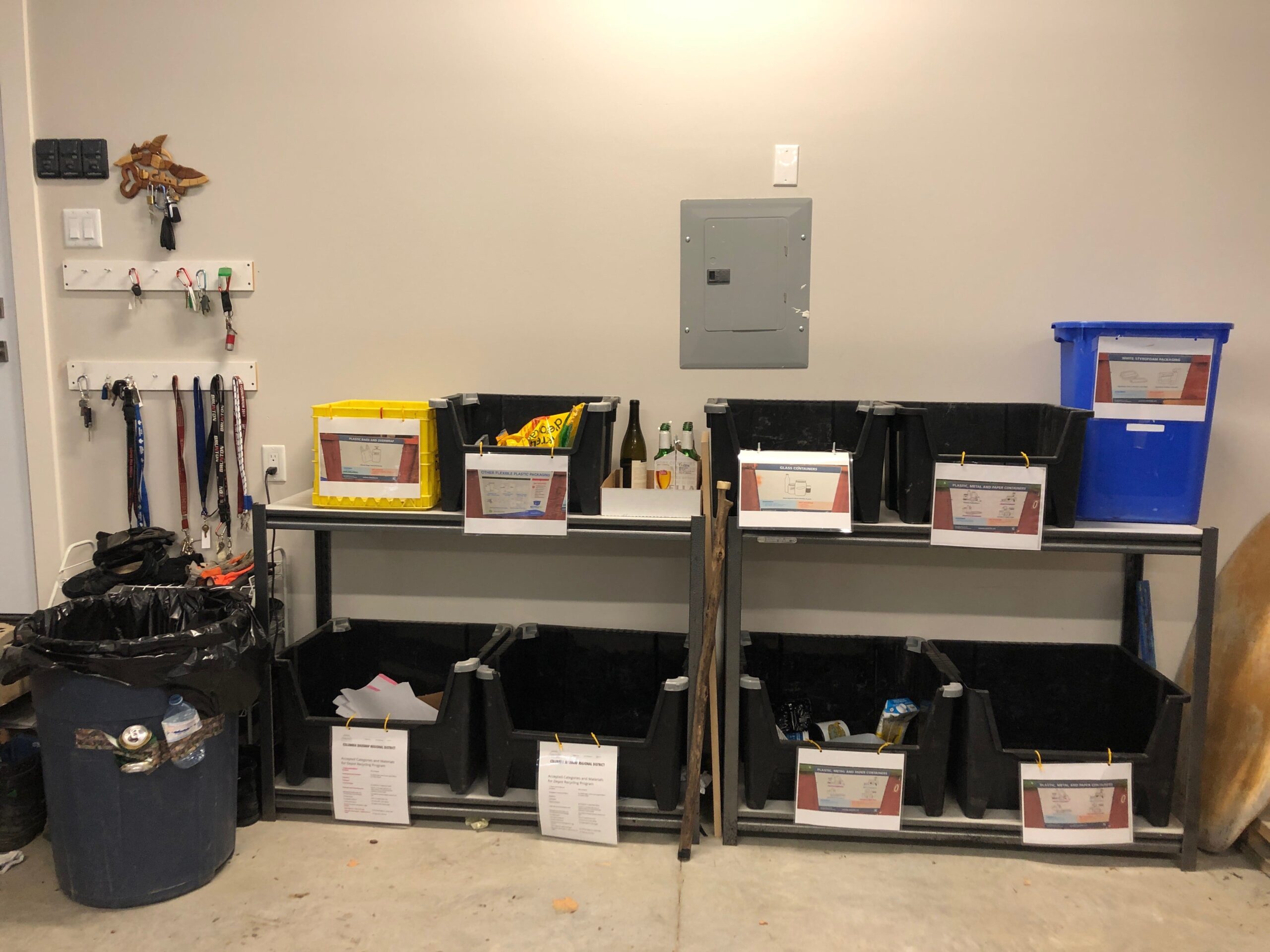 recycling set up in garage on shelving with separate containers for different categories of recyclable material